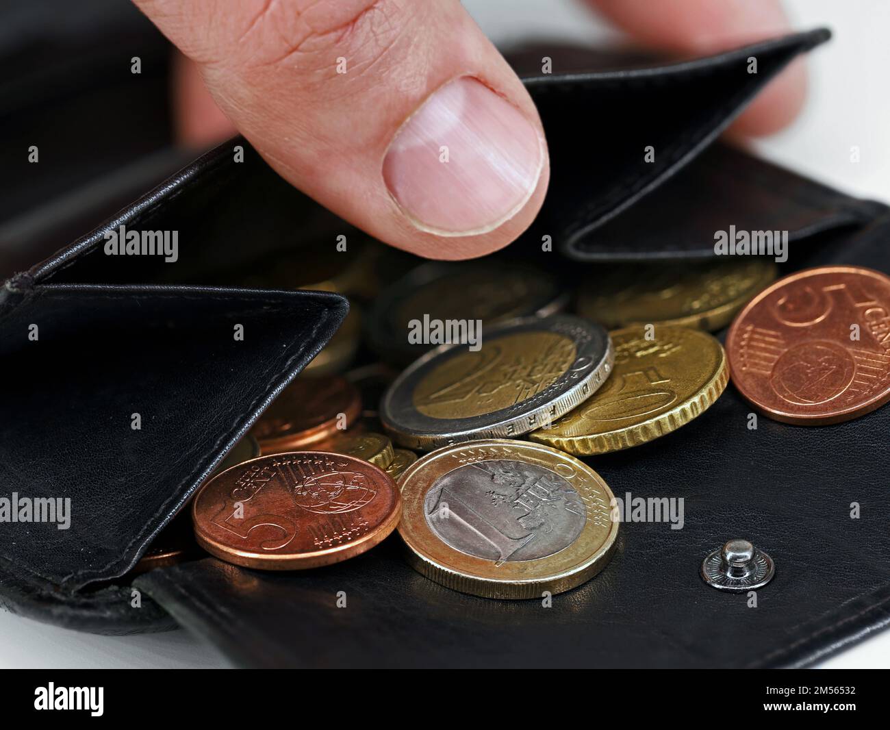 Male hand checking black leather wallet with euro coins, close-up of a open purse with loose change Stock Photo
