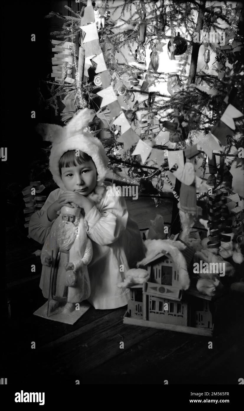 Penza region, USSR - circa 1955: little girl sitting under Christmas tree in white dress Stock Photo