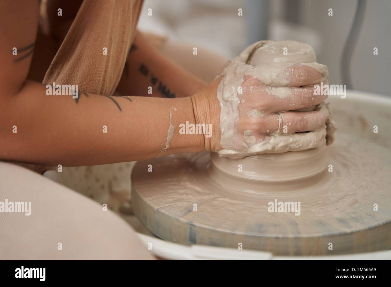 Closeup view of a woman modelling clay on potters wheel in a ceramic