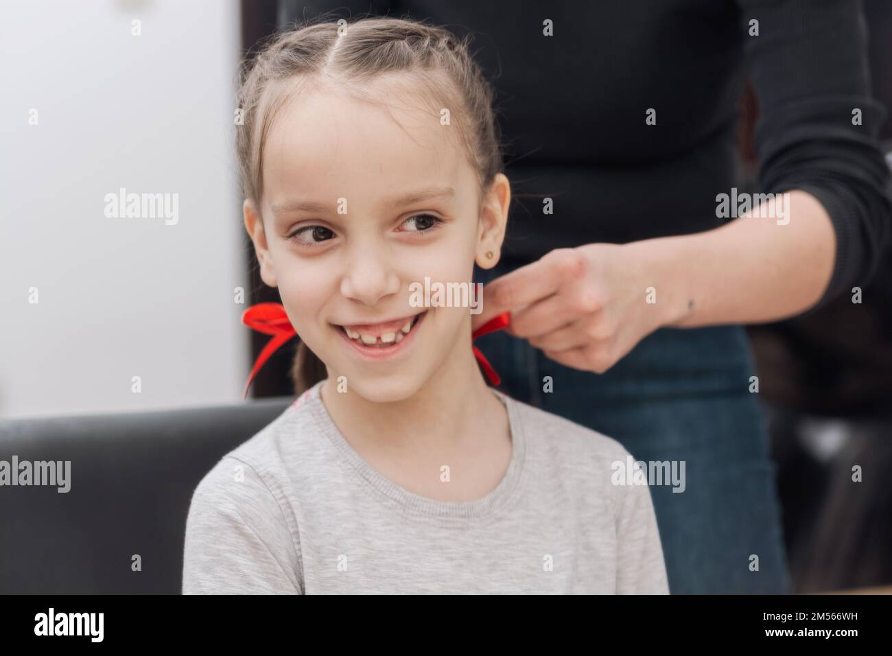 Hair salon, hairdresser makes hairdo braids for small girl in barber