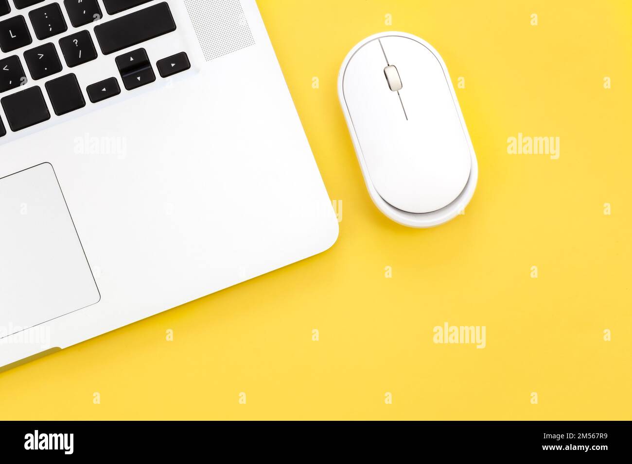 Computer mouse and laptop on a yellow background isolated, flat lay. Stock Photo