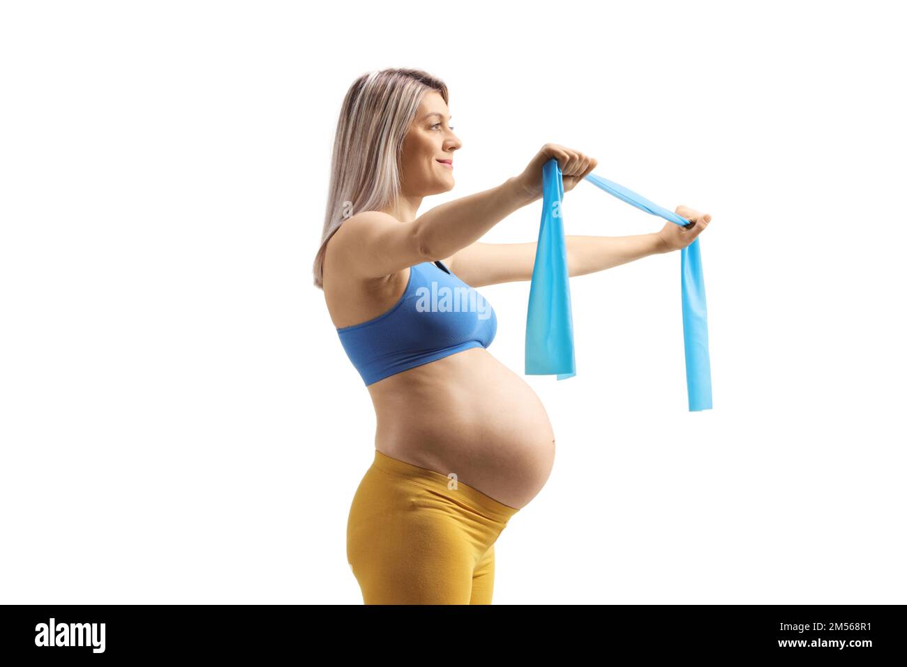 Profile shot of a pregnant woman exercising with a stretching band isolated on white background Stock Photo