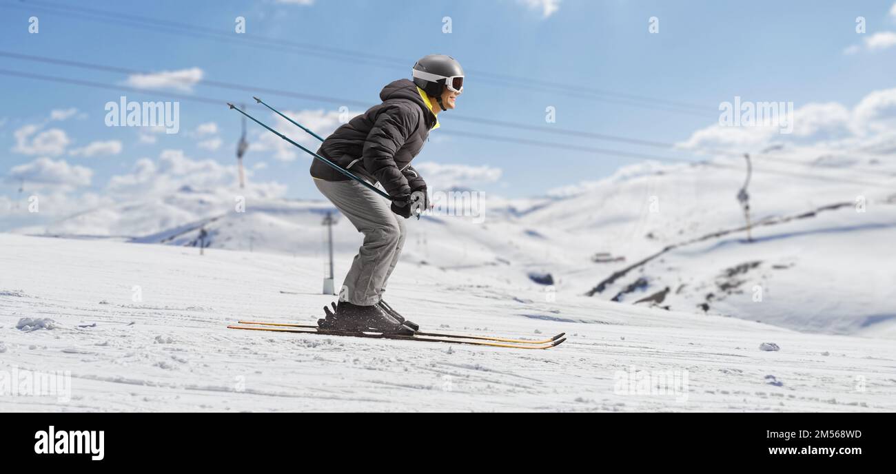 Full length profile shot of a man skiing in a ski resort Stock Photo