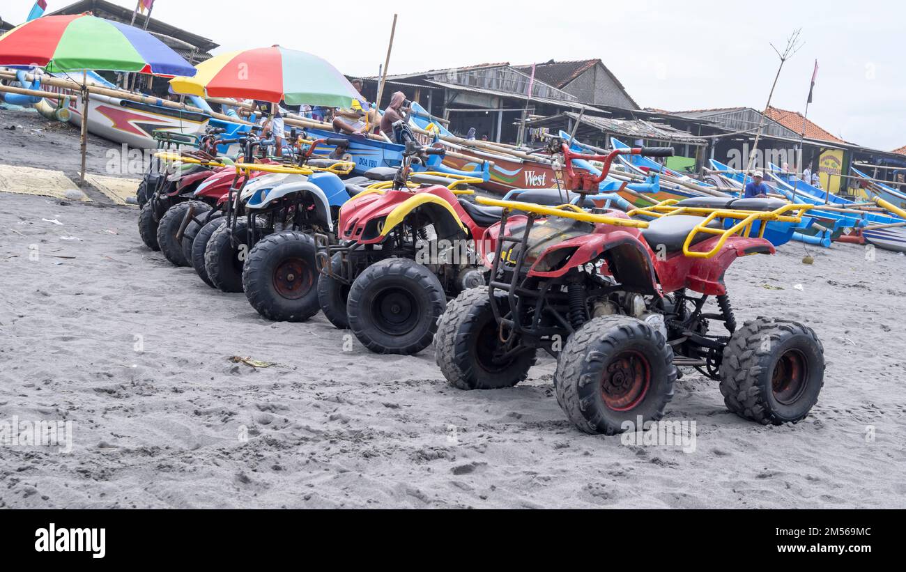 Yogyakarta, Indonesia - March 27, 2022: ATV motorcycles and fishing boats neatly lined up on Depok beach Stock Photo