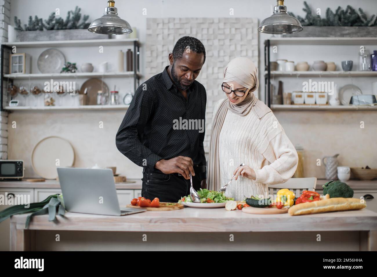Attractive african man and young muslim woman holding spoons and mixing