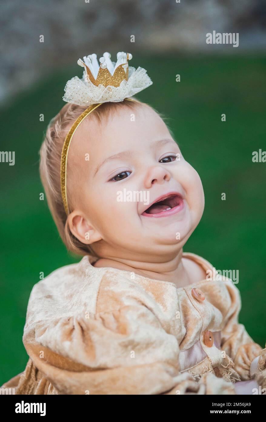 charming baby in princess costume with a crown on head is laughs Stock