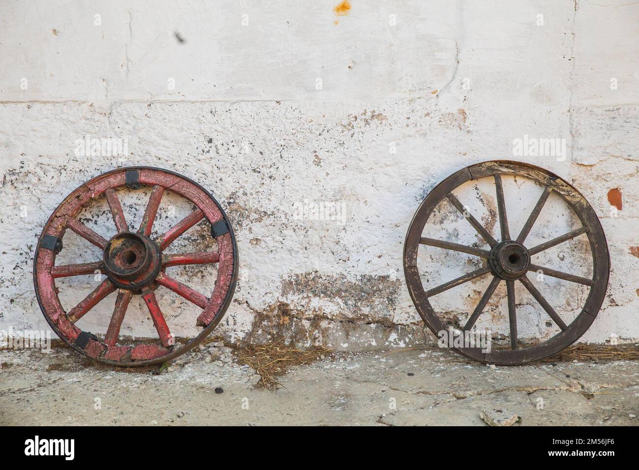 Rotten wooden wheels near the shabby barn wall Stock Photo