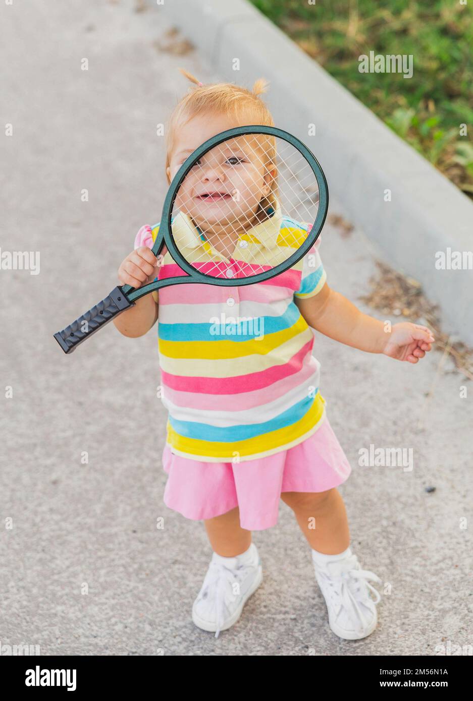 charming little tennis player covered by racket Stock Photo