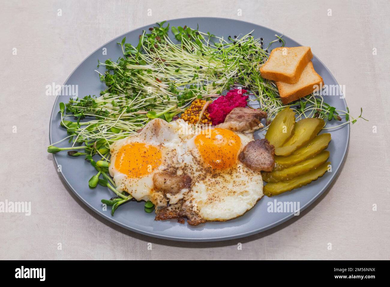 scrambled eggs with bacon, micro green, mustard and pickled cucumber