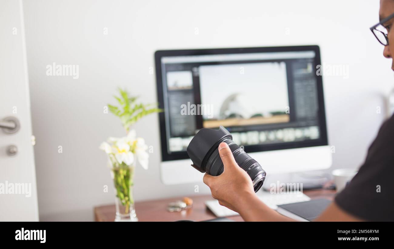 A young photographer looking at target in his hand while working on computer Stock Photo