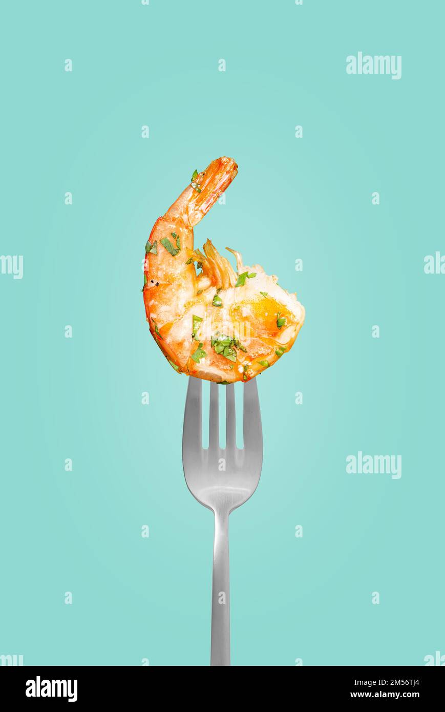 Baked shrimp on a fork isolated on a blue background, grilled shrimp on a fork. Poster for a restaurant Stock Photo