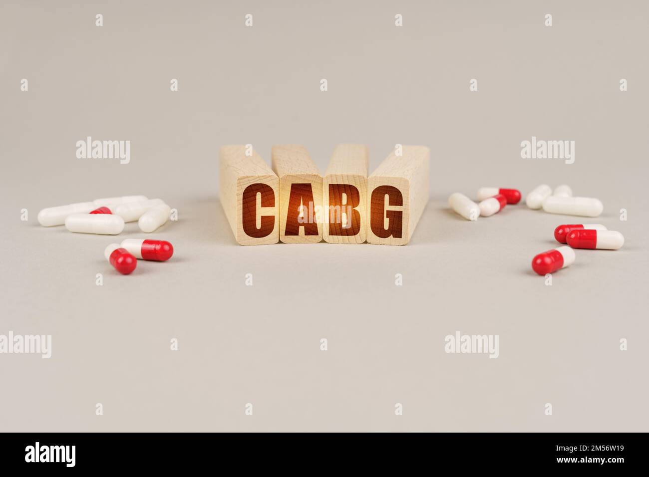 Medical concept. On a gray surface are pills and a red wooden block with the inscription - CABG Stock Photo