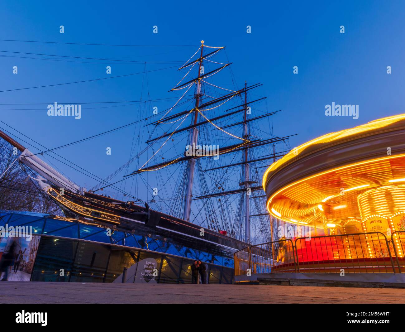 London, Greenwich, England - December 26, 2022: Christmas scene with a carousel in motion in front of the Cutty Sark ship in Greenwich peninsula Stock Photo