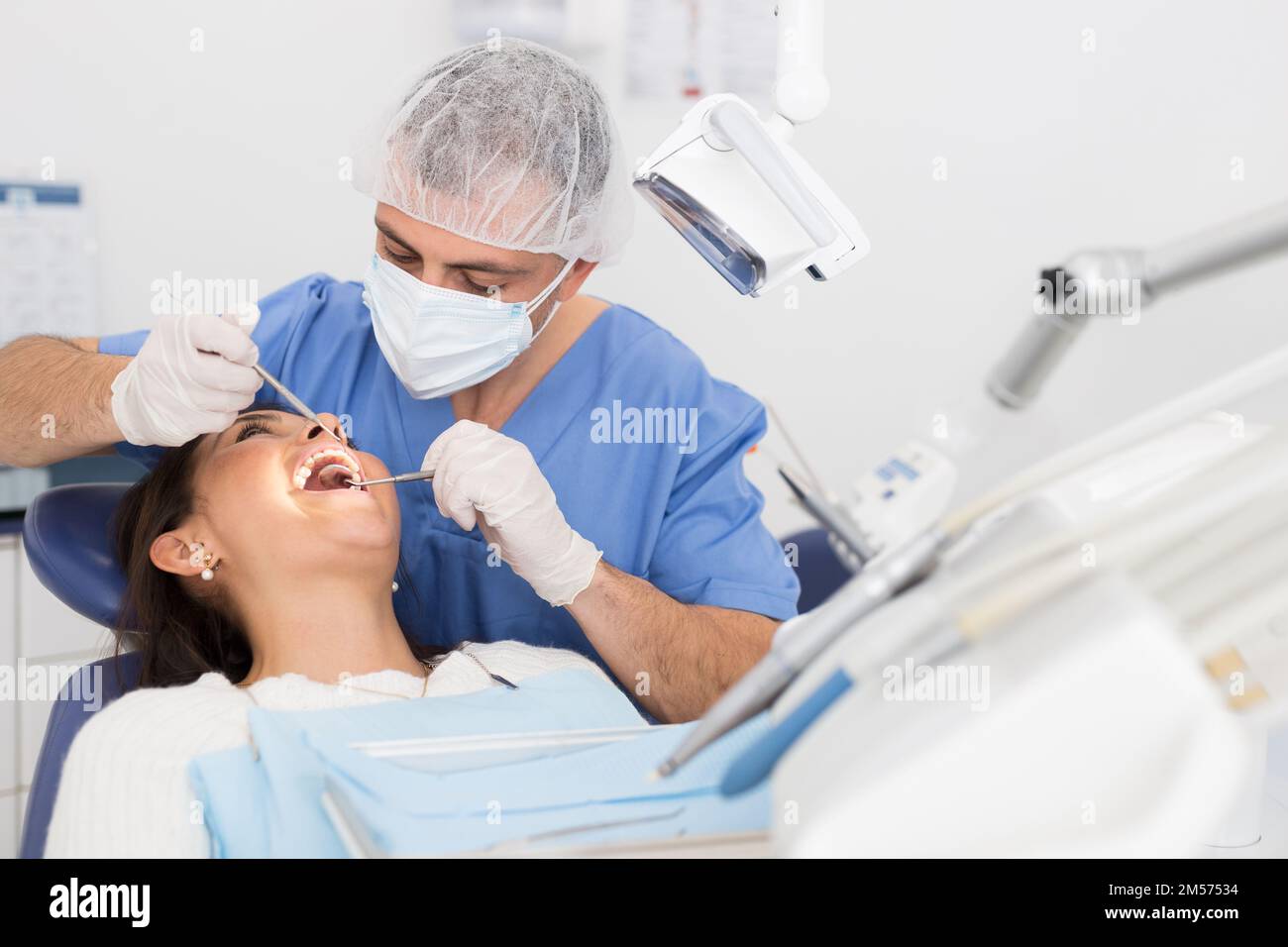 Dentist man examining a latin female patient teeth Stock Photo Alamy