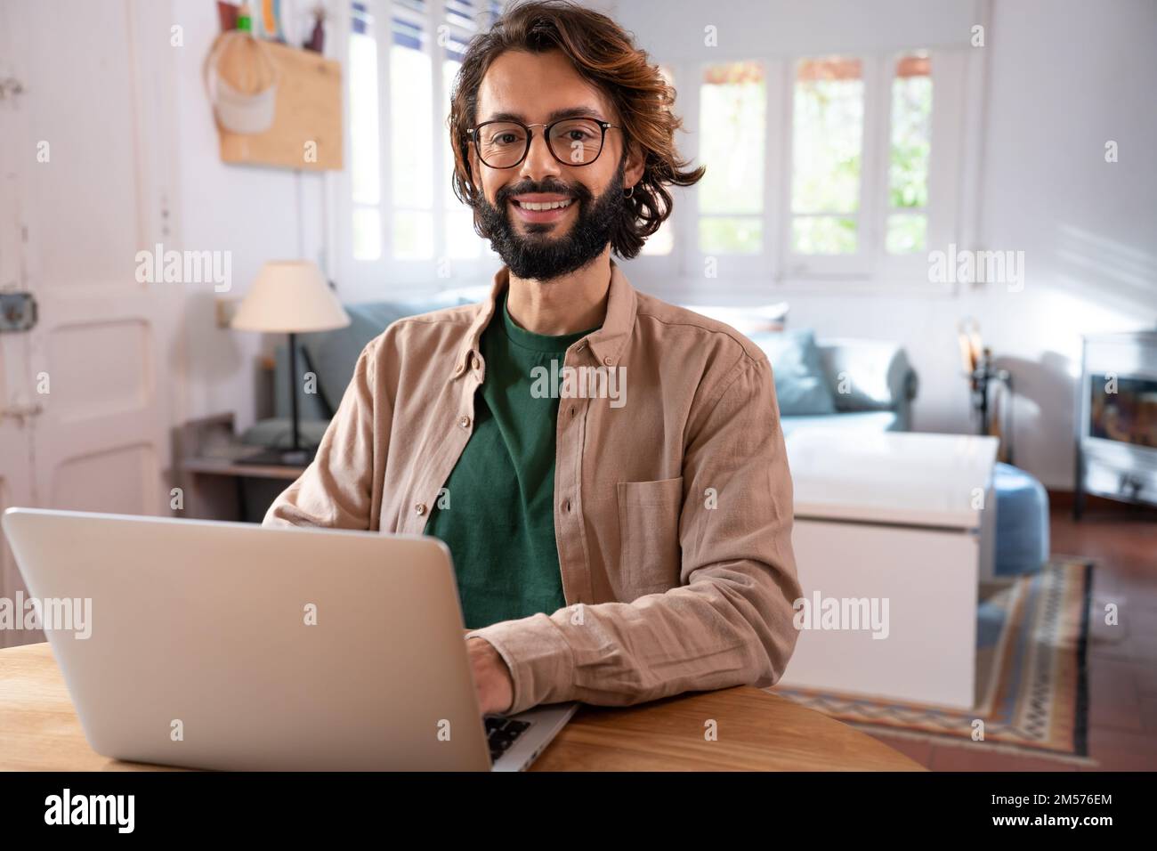 Cheerful young programmer looking at camera while working at his home Stock Photo