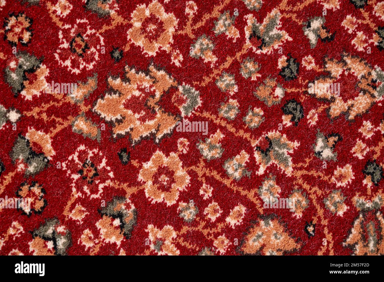 Close up of details of intricate patterns with floral ornament of short pile colorful rug. Texture of red, ornate persian carpet for background, fragment. Concept of textures and background. Stock Photo