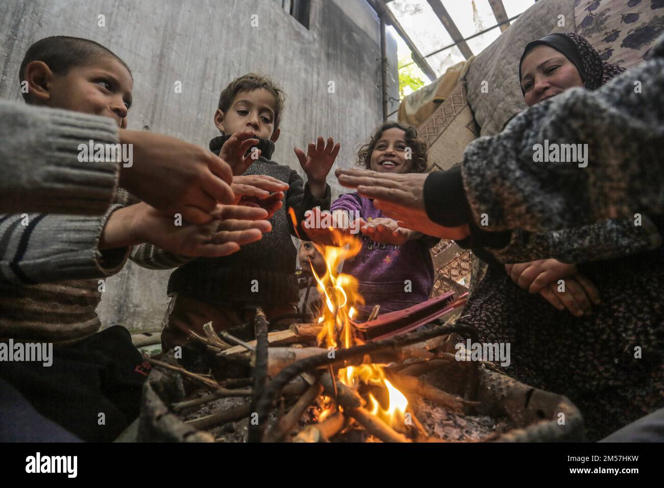 Palestinian refugees warm themselves by a fire near their temporary ...