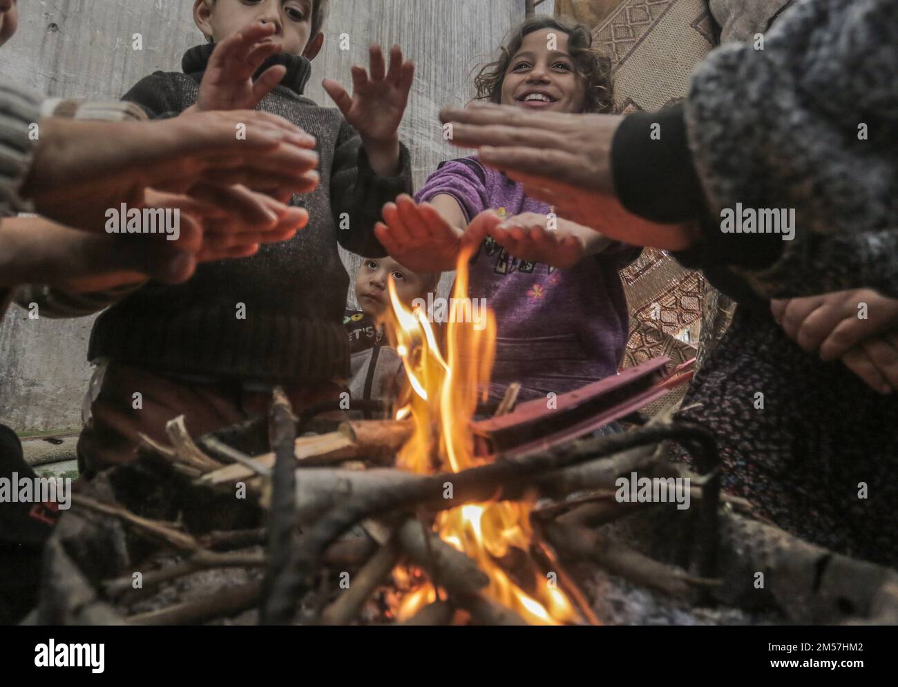 Palestinian refugees warm themselves by a fire near their temporary ...