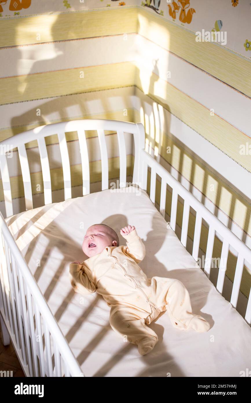 Cryng baby in the bed. Silhouette of a mother and pacifier Stock Photo