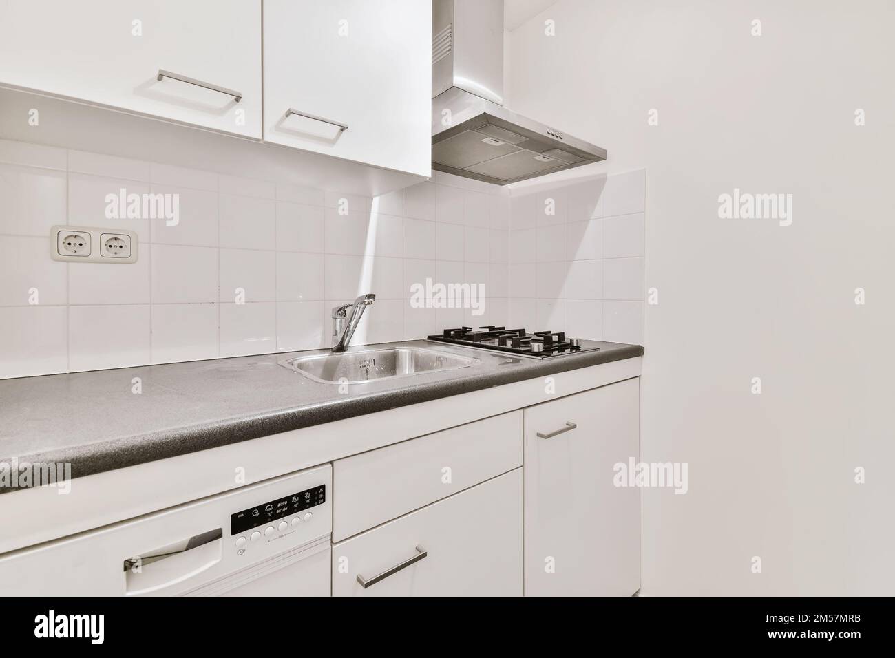 a kitchen with white cabinets and black counter tops on the counters in front of the dishwasher there is an appliance Stock Photo