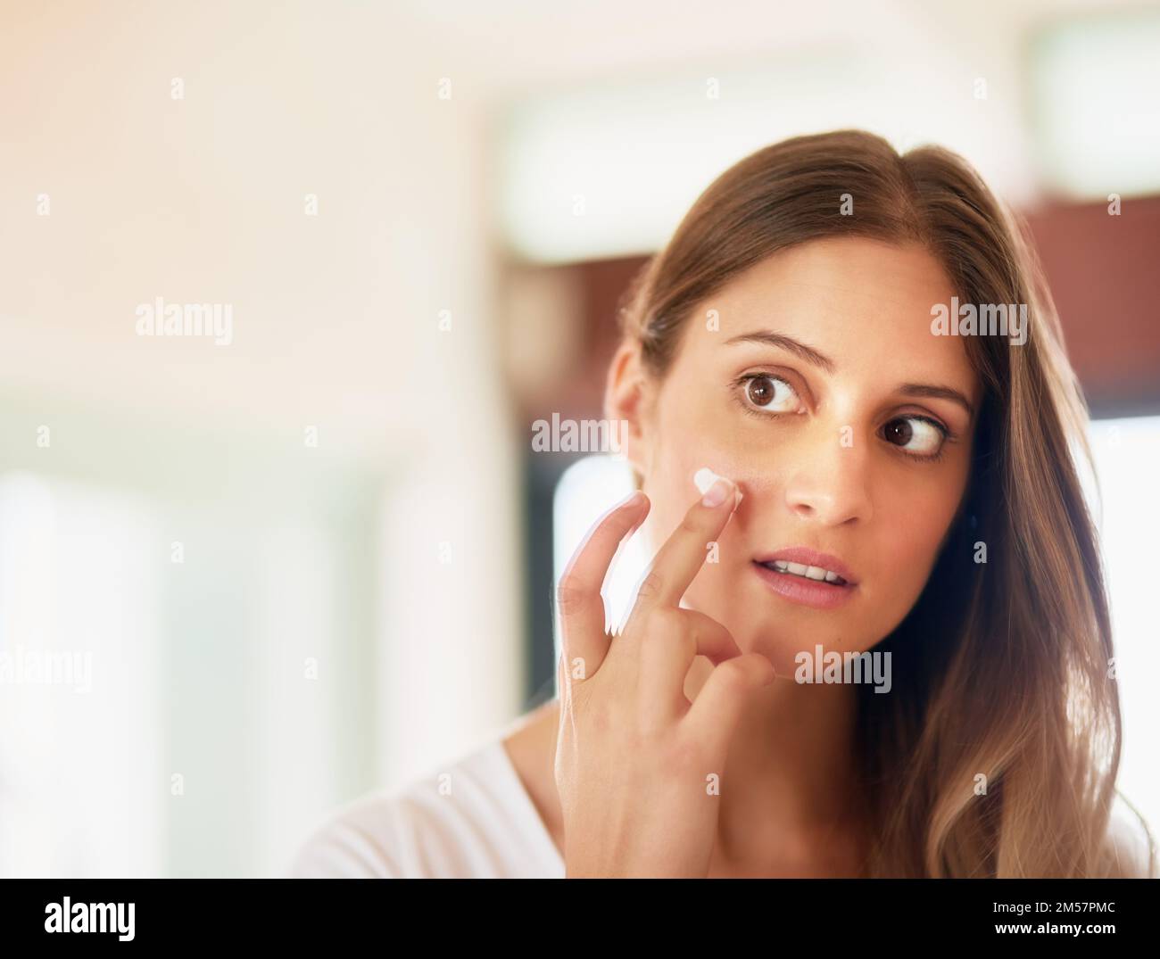 Cleanse, tone, and moisturise to protect your healthy skin. a young woman applying moisturiser to her face. Stock Photo