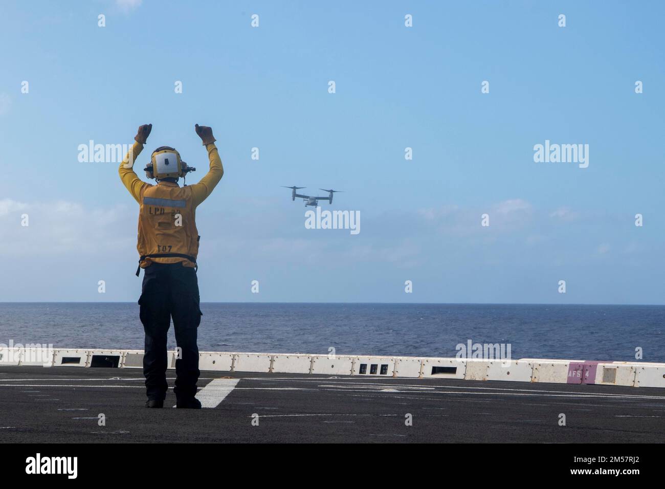 PACIFIC OCEAN (Nov. 18, 2022) — Aviation Boatswain’s Mate (Handling) 3rd Class Quantae Thompson directs an MV-22 Osprey assigned to Marine Medium Tiltrotor Squadron (VMM) 362 to land on the flight deck of amphibious transport dock USS Anchorage (LPD 23), Nov. 18, 2022. The ability to operate seamlessly and simultaneously on the sea, ashore, and in the air represents the unique value of amphibious capability provided by the amphibious ready group and Marine expeditionary team. The Makin Island ARG, comprised of amphibious assault ship USS Makin Island (LHD 8) and amphibious transport docks Anch Stock Photo
