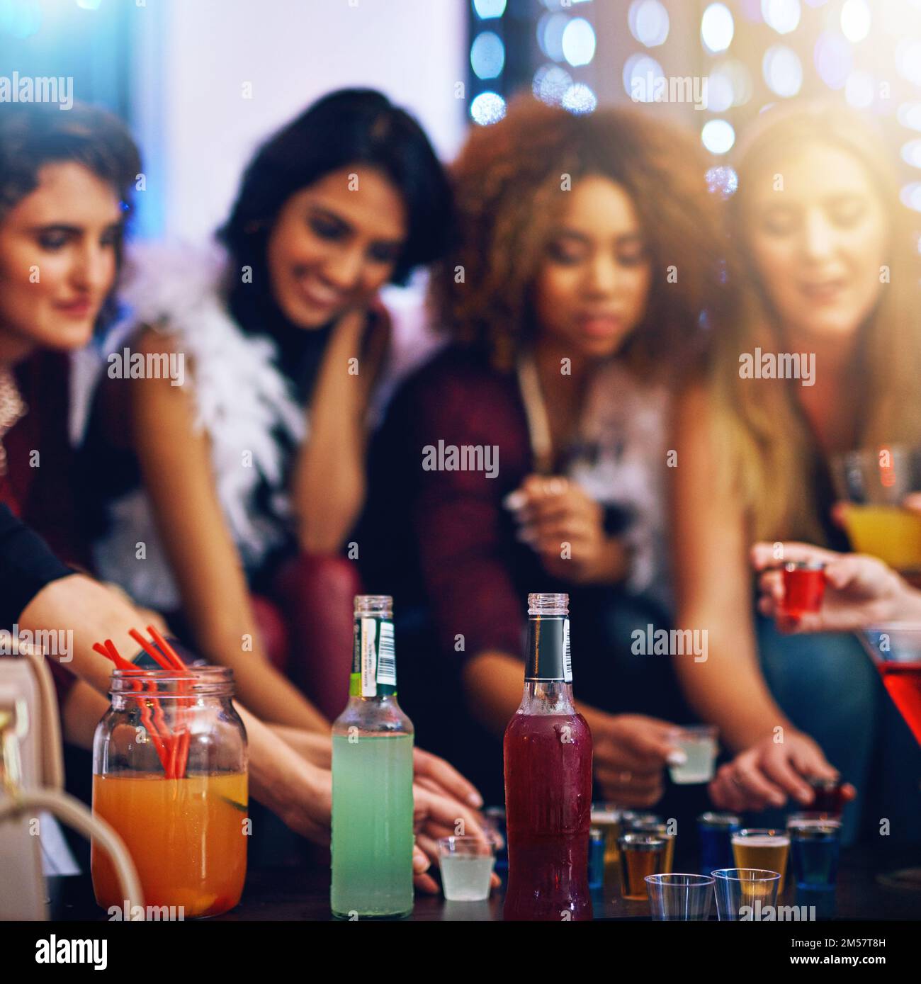 Fill your glasses ladies. a group of friends having shots together at a party. Stock Photo