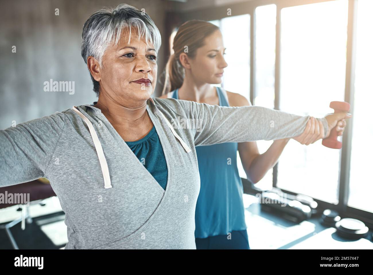 Retired, not tired. a senior woman using weights with the help of a physical therapist. Stock Photo