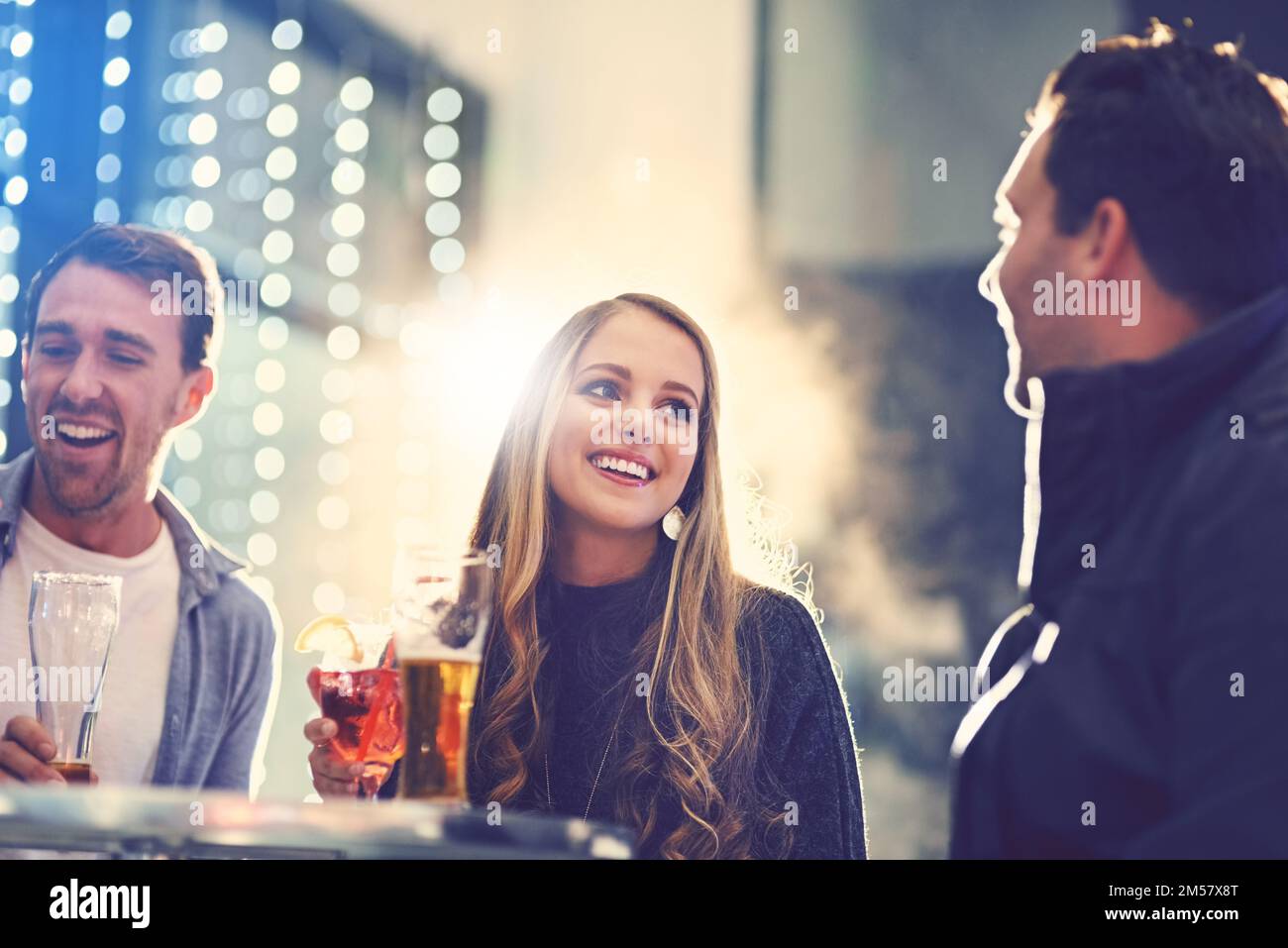 Music, drinks and good company. a group of friends relaxing with cocktails in a Stock