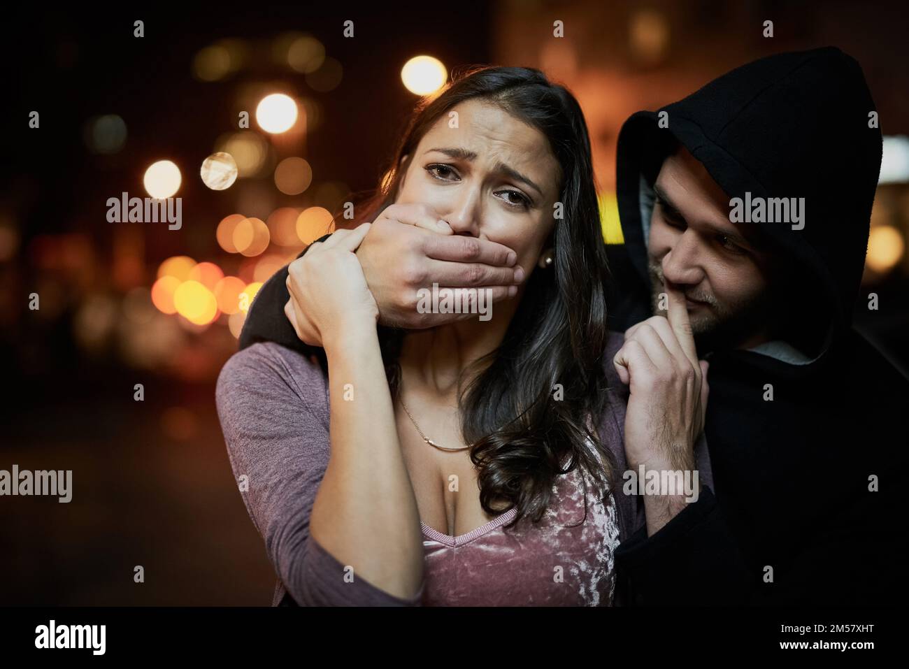 Shes frightened for her life. Portrait of a frightened young woman with her assailants hand over her mouth. Stock Photo
