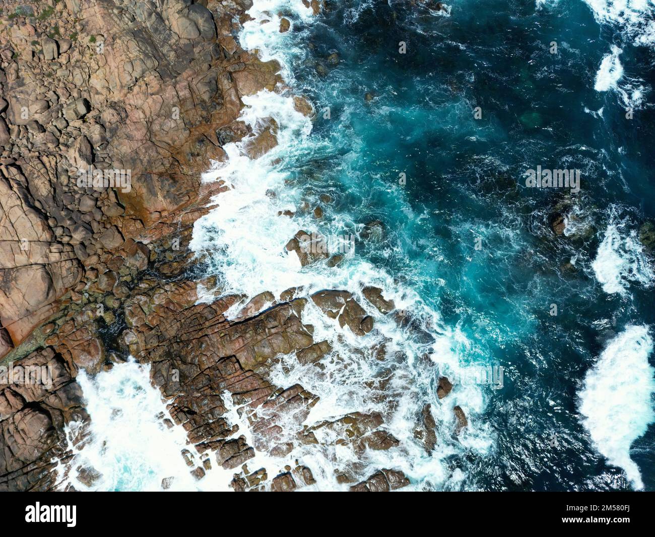 An aerial view of the coast with rocks and blue ocean waves in daylight ...