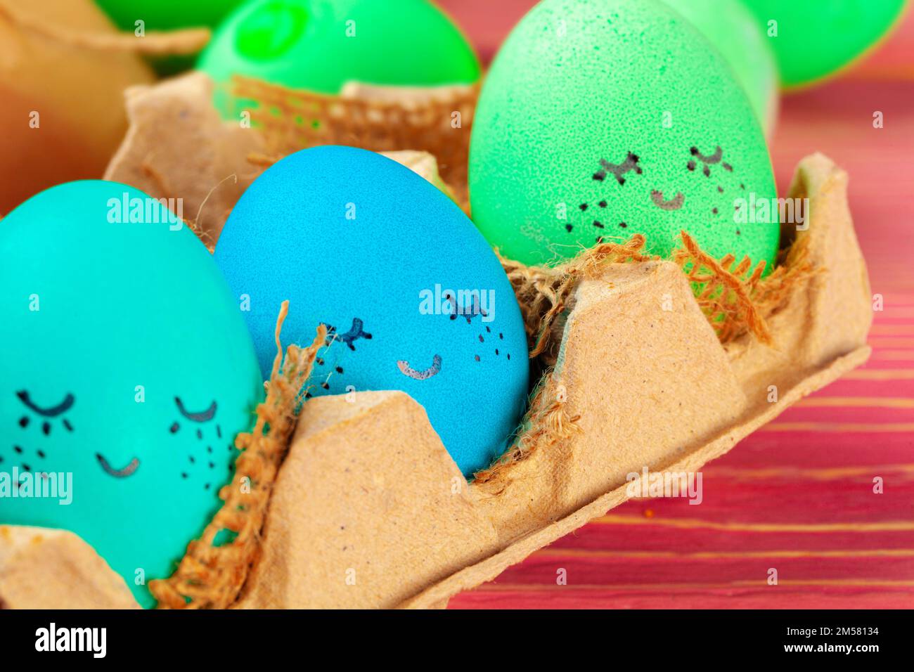 Blue and green colored Easter eggs with drawn funny faces Stock Photo