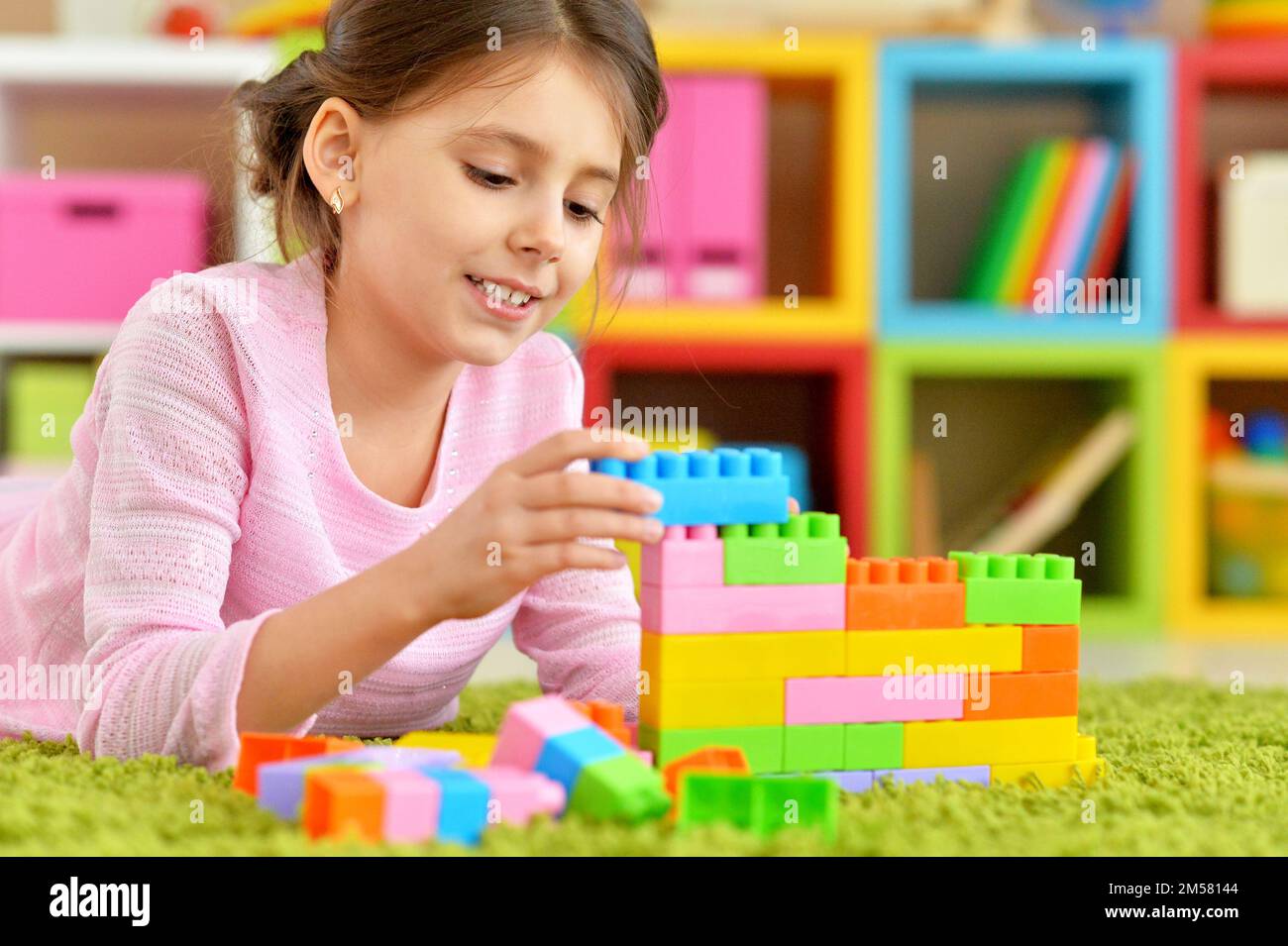 Curly little girl playing with colorful plastic blocks Stock Photo - Alamy