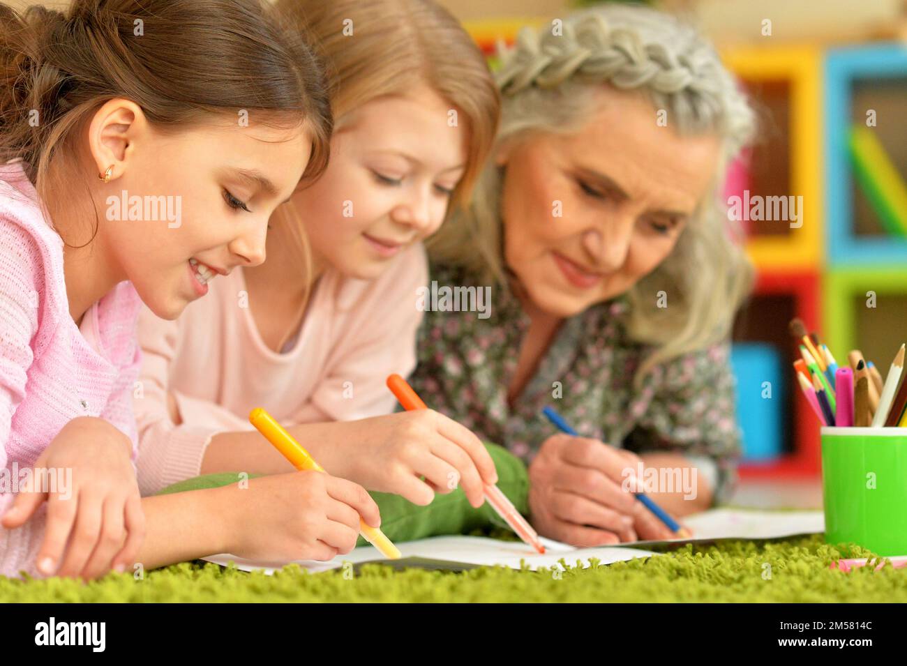 Old woman with tweenie girls drawing at home Stock Photo