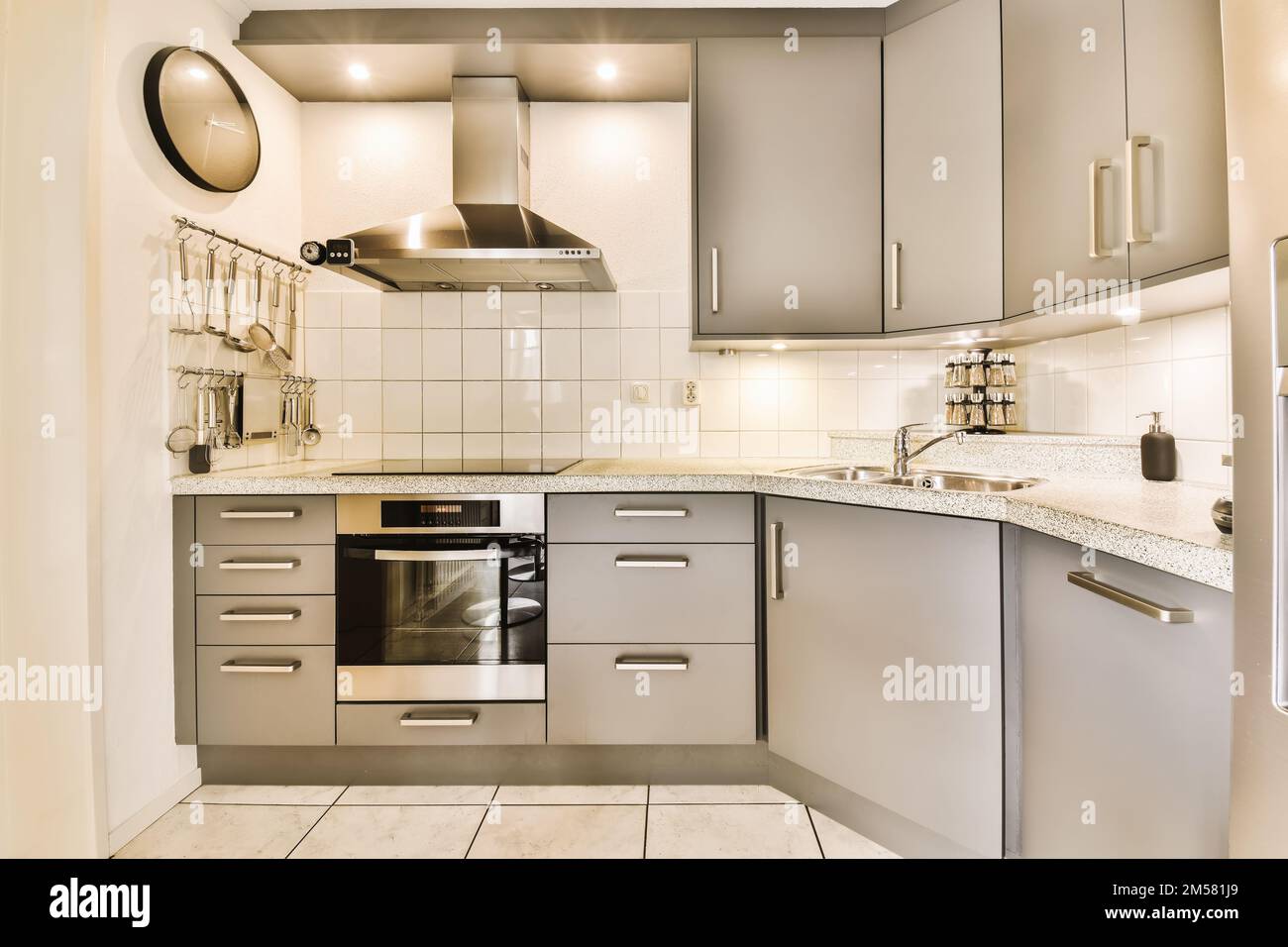 a small kitchen with white tile flooring and stainless steel appliances on the counters in the room is very clean Stock Photo