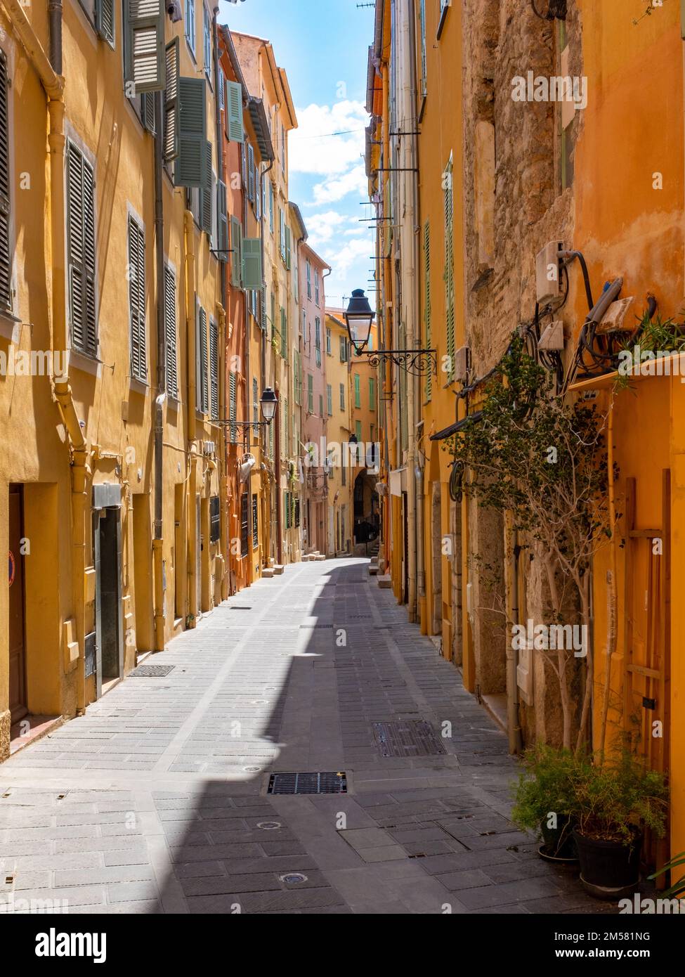A colourful straight street of the old Menton, France with no people. Taken on a sunny spring day. Stock Photo
