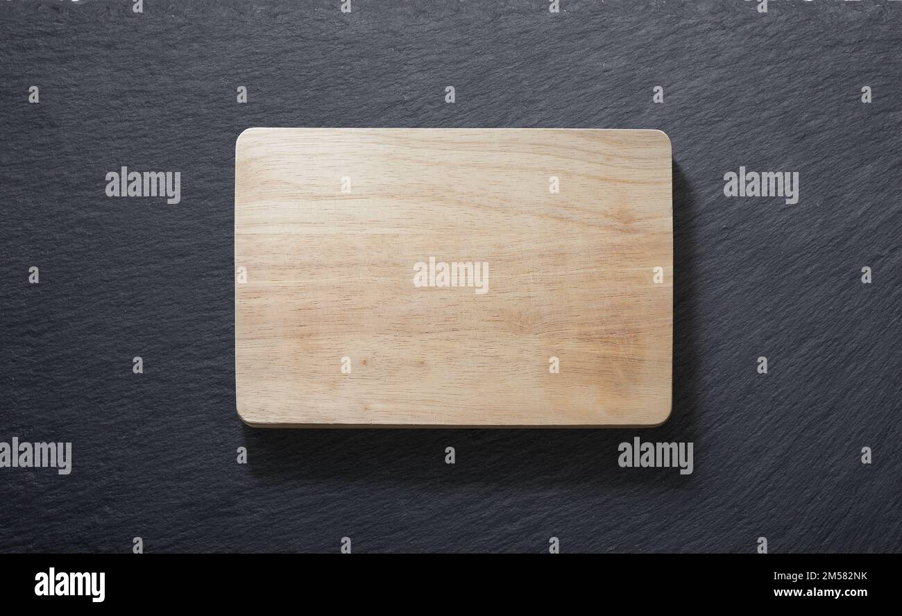 Wooden cutting board against a slate plate from above Stock Photo