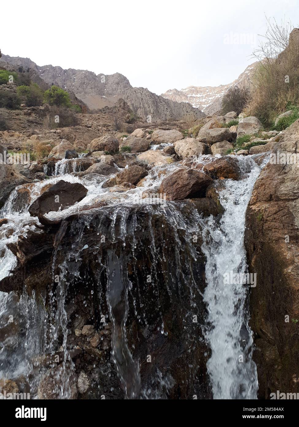 A vertical shot of a waterfall flowing down a steep rocky hill Stock ...