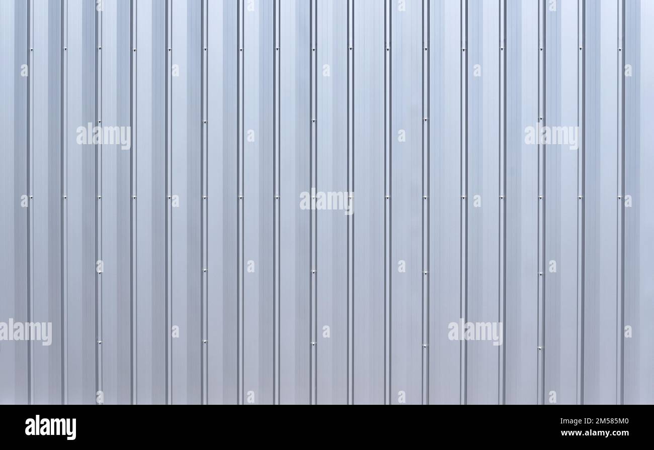 Silver colored aluminum wall paneling with vertical grooves and hex bolts Stock Photo
