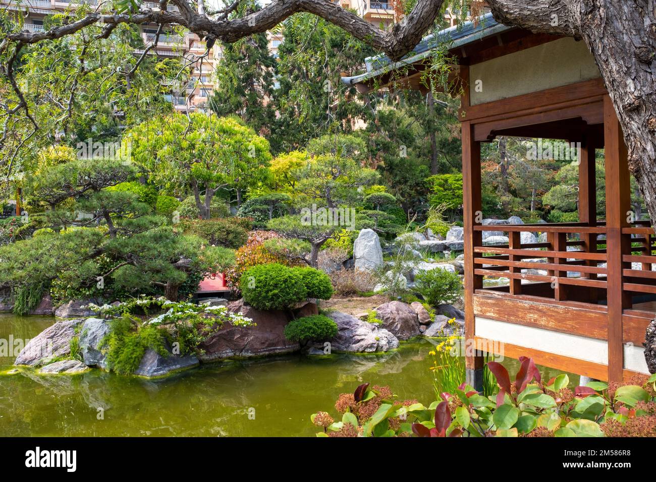 Monaco - May 3, 2022: A wood pavilion is overlooking a pond of the Japanese garden of Monaco. Taken on a sunny spring day. Stock Photo