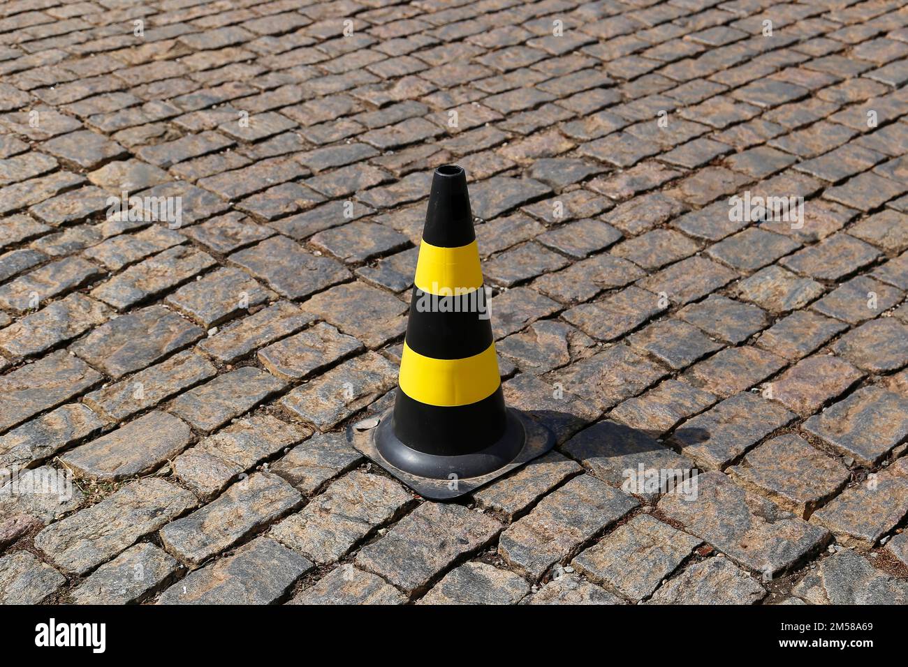 traffic signal cone yellow and black colors, hard plastic, on stone public road Stock Photo