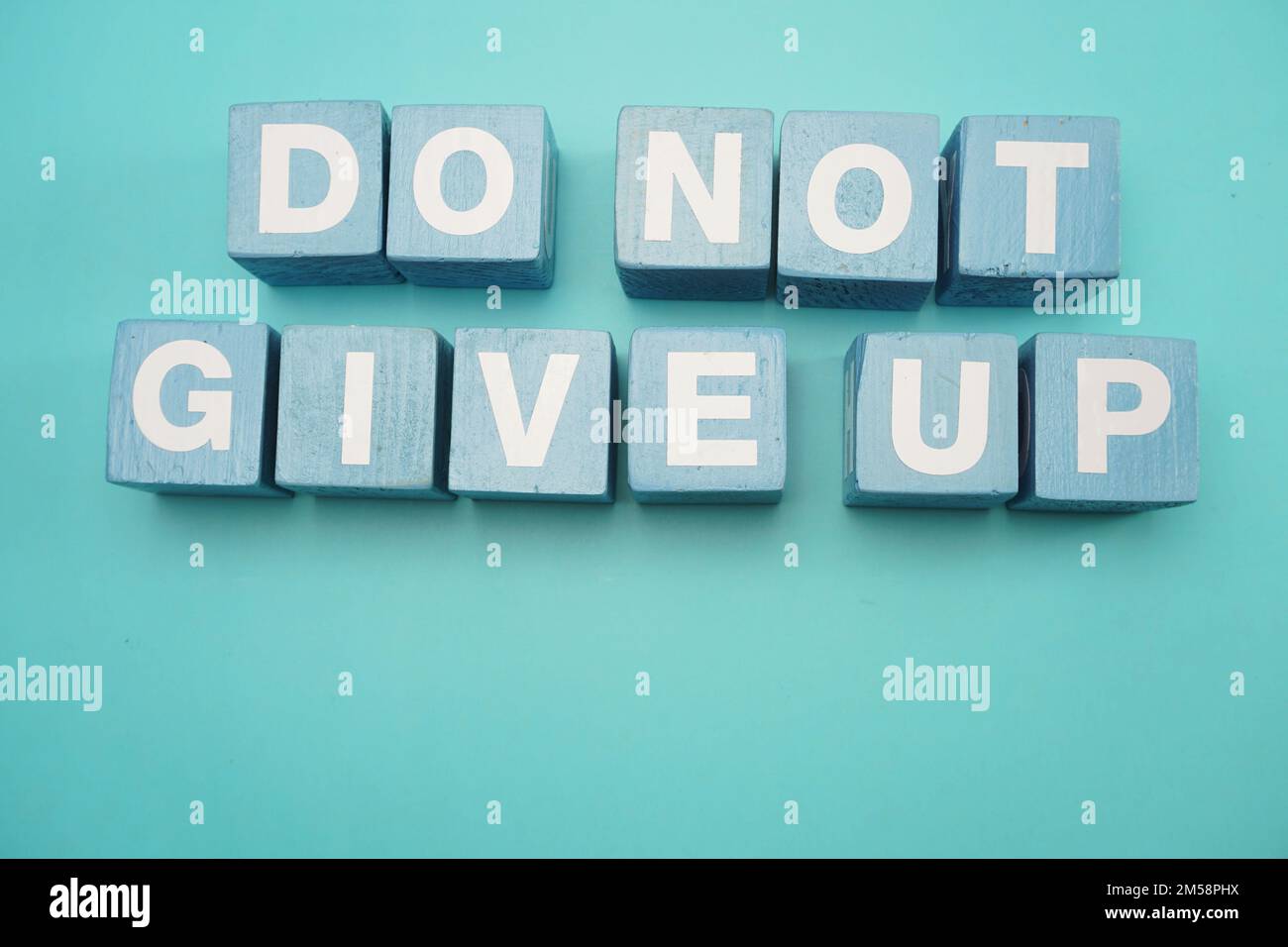 do-not-give-up-word-made-from-wooden-cubes-with-letters-alphabet-on-blue-background-stock-photo