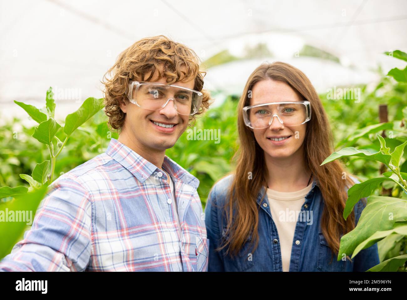 Happy couple of agriculturists photographing themselves in the greenhouse Stock Photo