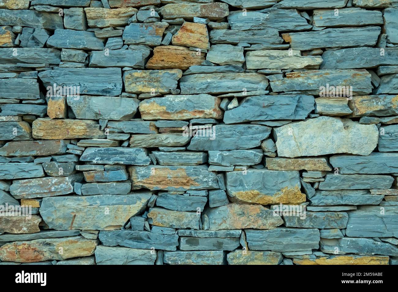 wall of mixed gray and assorted-colored rocks texture background. Stock Photo