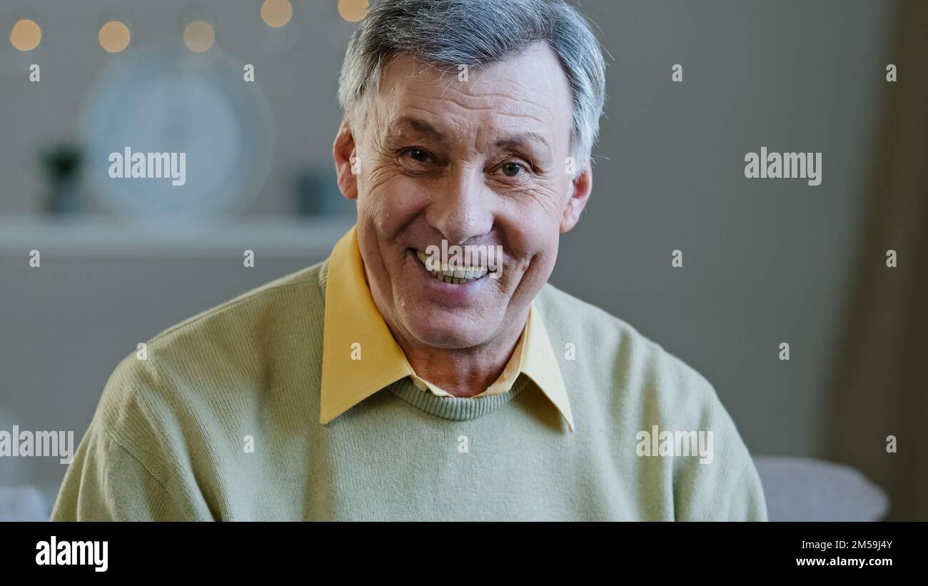 Happy elderly middle aged man make video call recording vlog remotely communicate in online chat senior 60s grandpa smiling wave hand looking at Stock Photo