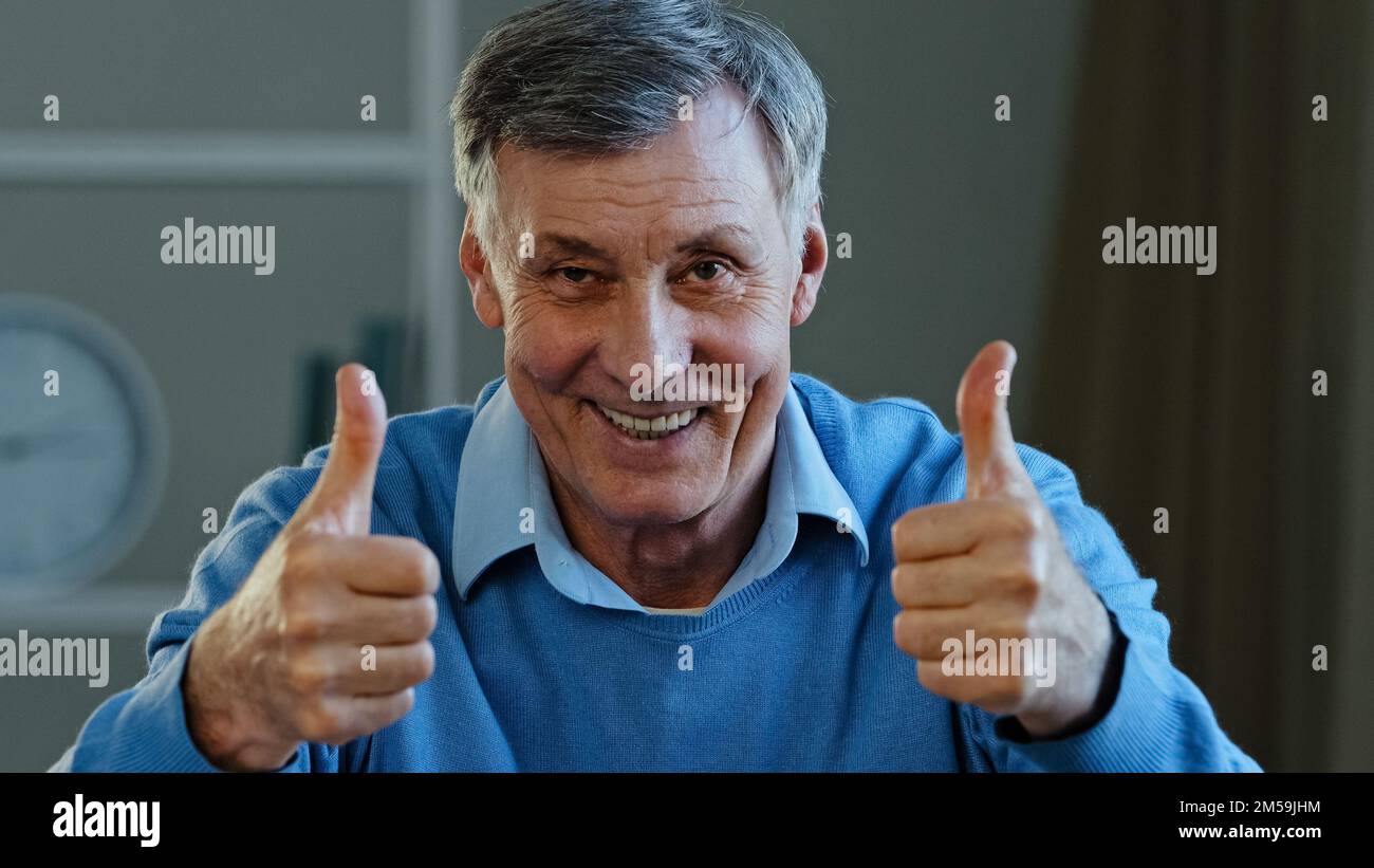 Portrait of happy mature elderly man showing two thumbs up smiling pensioner looking at camera demonstrate affirmative supportive gesture positive Stock Photo