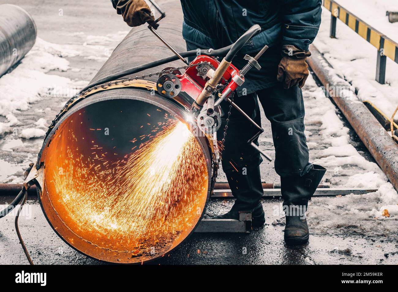 Working welder cuts metal and sparks fly. Gas cutting of large diameter pipes with acetylene and oxygen. Industrial metal cutting in oil and gas industry. Stock Photo