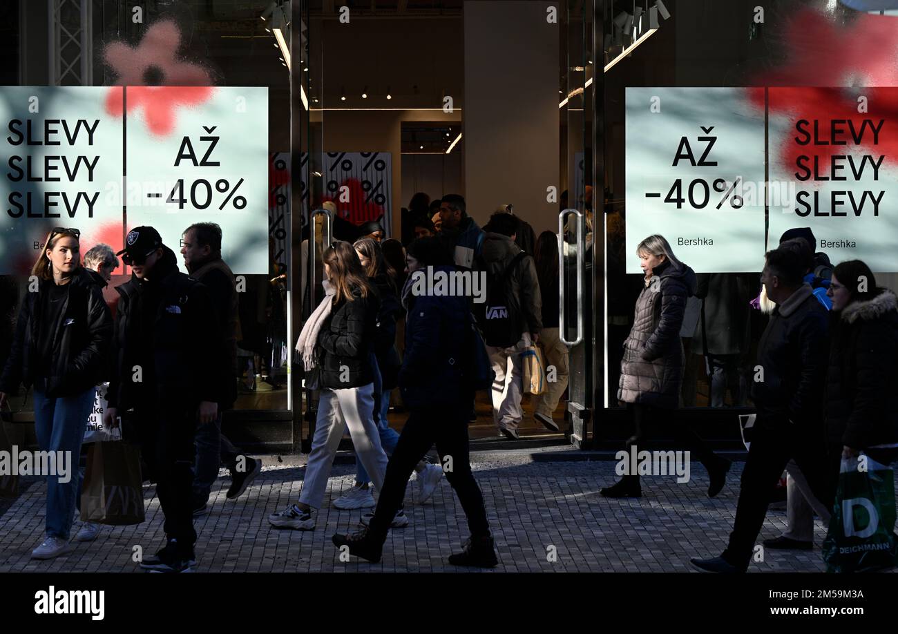 Prague, Czech Republic. 27th Dec, 2022. People walk past a shop window with  discount banners, 27 December 2022, Prague. Post-Christmas sales have  started in brick-and-mortar stores. Shop with signs warning about the