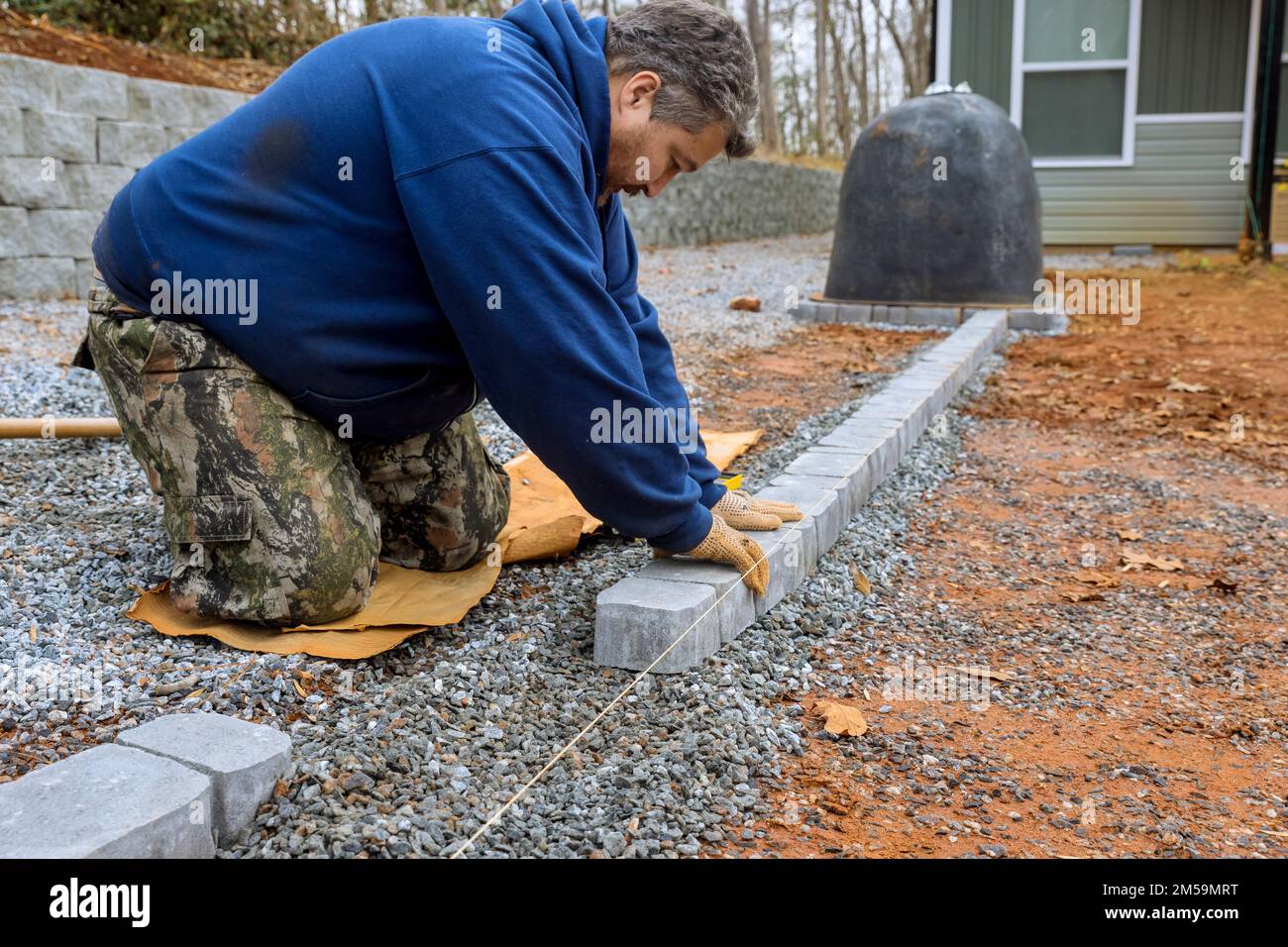 Professional paver worker lays stones for paving pathway in yard of master. Stock Photo