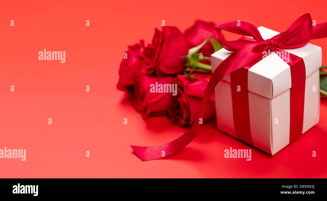 Valentines day card with gift box and rose flowers. On red background ...